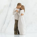 Willow Tree® Faceless couple standing holding hands facing one another - she is in white dress, he is in white shirt and brown pants