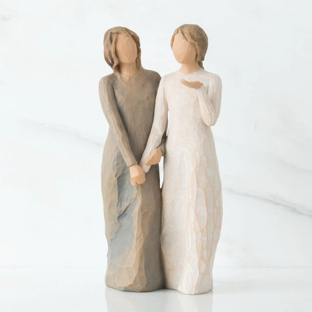 Willow Tree® Two faceless woman figurines standing facing forward holding hands - left one is wearing light brown dress, right one is wearing white dress