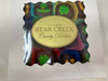 Box of Bear Creek Candy Kitchen chocolates with colorful wrappers on a white background