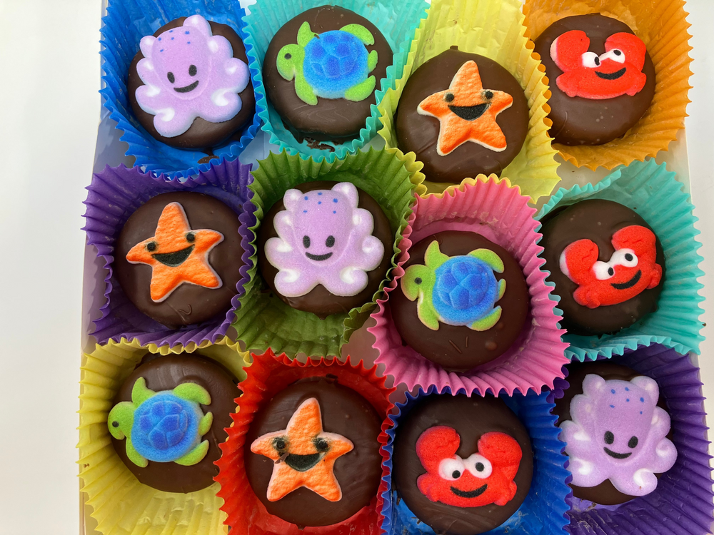Assorted chocolate candies with colorful decorations in various shaped paper cups.