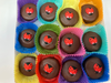 Chocolate candies with ladybug designs in colorful paper cups on a white background