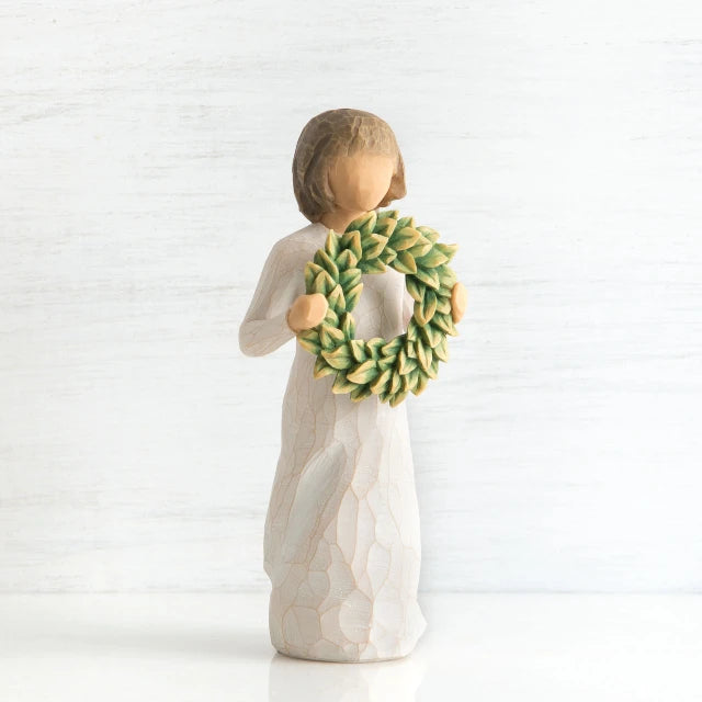 Willow Tree® Front view of young girl with bangs and short brown hair holding up a green, leafy wreath