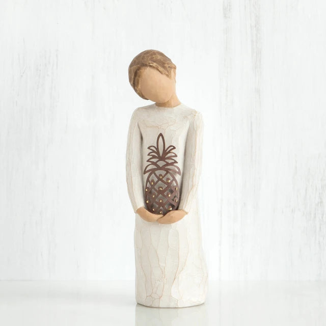 Willow Tree® Front view of girl with brown hair in a bun holding a pineapple with both hands