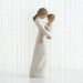 Willow Tree® Side view of faceless mom figurine wearing white dress holding child in white outfit in her arms
