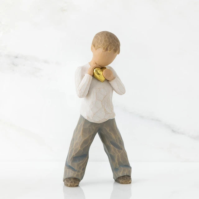 Willow Tree® Young boy faceless figurine in white shirt and blue jeans holding gold heart figurine standing up