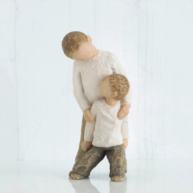 Willow Tree® Two small boy figurines wearing white shirts and brown pants -one is standing over holding the other
