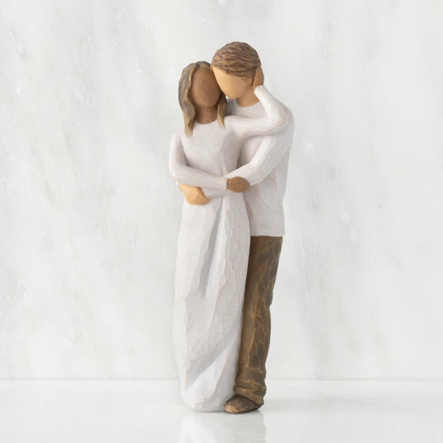 Willow Tree® Front view of couple, standing with arms around each other. Woman has darker skin and hair; man has lighter skin and hair.