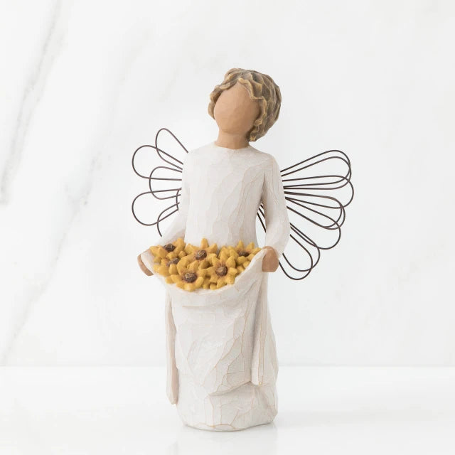 Willow Tree® Front view of angel with tied back, curly, dark brown hair holding up a portion of her dress's skirt as it is full of sunflowers