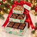 Bear Creek Candy Kitchen three-box Christmas candy tower in mint-green gingerbread-pattern boxes with red lids and a red bow, containing pecan pralines, pecan turtles, and chocolate fudge.