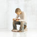 Willow Tree® Young faceless boy figurine sitting on books with book opened in his hands - another book on the floor of his feet