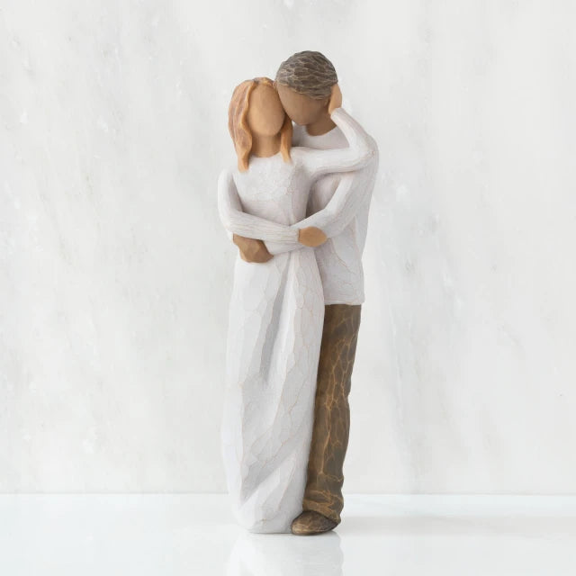 Willow Tree® Front view of couple, standing with arms around each other. Woman has lighter skin and hair; man has darker skin and hair.