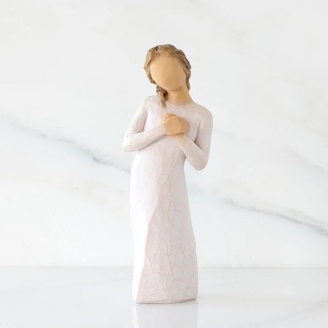 Willow Tree® Front view: Standing figure in cream dress with hands to heart in empathetic gesture