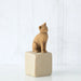 Willow Tree® Golden cat figurine sitting on white rock