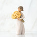 Willow Tree® Front/side view of little girl with short brown hair holding a large bouquet of yellow roses