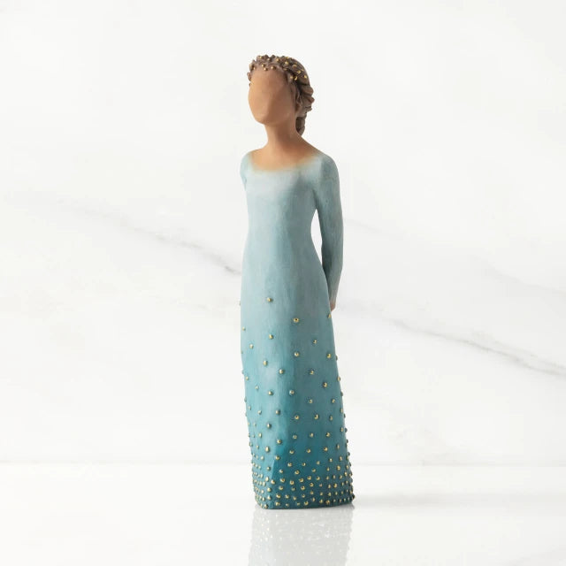 Willow Tree® Front/left view: Darker-skin figure, arms clasped behind back, hair and deep blue ombré garment dotted with gold leaf