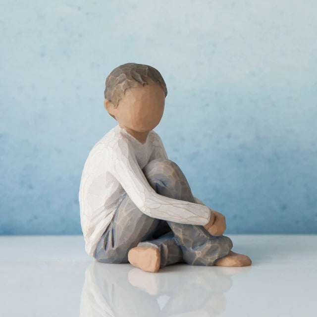 Willow Tree® Faceless young boy figurine sitting down wearing white shirt and blue jeans
