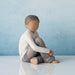 Willow Tree® Faceless young boy figurine sitting down wearing white shirt and blue jeans