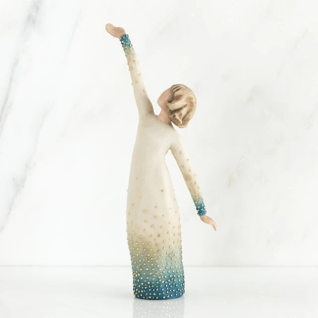 Willow Tree® Faceless woman figurine in white dress with blue embellishments - she is facing away from the camera holding both her arms in opposite directions
