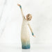 Willow Tree® Faceless woman figurine in white dress with blue embellishments - she is facing away from the camera holding both her arms in opposite directions