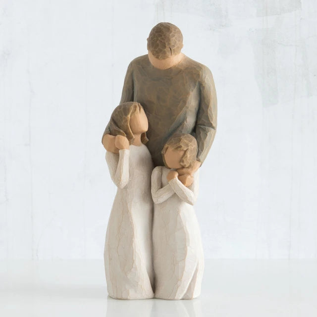 Willow Tree® Man faceless figurine wearing brown shirt standing over two faceless girl figurines in white dresses