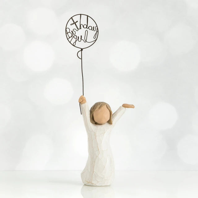 Willow Tree® Front view of little girl with brown hair and both arms in the air as she holds a wire balloon. Text on balloon is wire