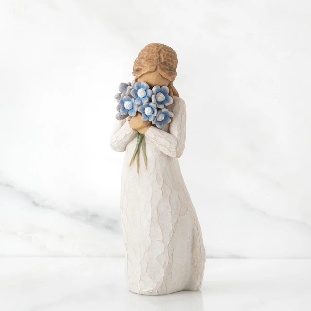 Willow Tree® Front view of woman with tied back brown hair holding a cluster of blue flowers up to her face
