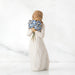 Willow Tree® Front view of woman with tied back brown hair holding a cluster of blue flowers up to her face