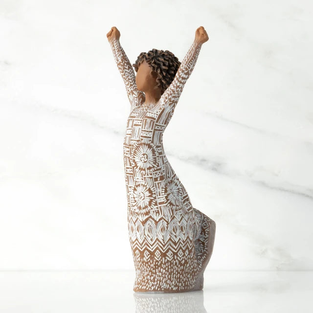 Willow Tree® Figure turned to left, with dark natural hairstyle, arms raised overhead, dress entirely etched with African textile patterns
