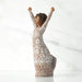 Willow Tree® Figure turned to left, with dark natural hairstyle, arms raised overhead, dress entirely etched with African textile patterns