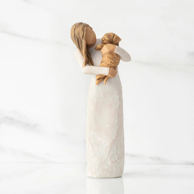Willow Tree® Front view, standing female figure in cream dress, holding golden color puppy in her arms