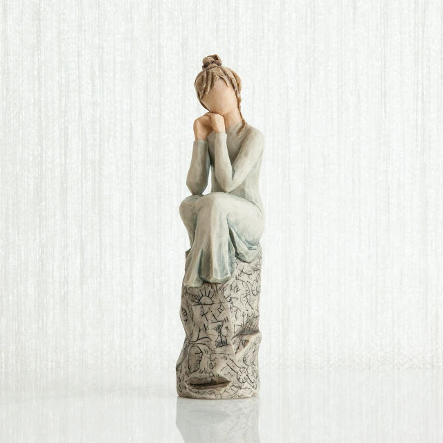 Willow Tree® Woman figurine with brown hair in a bun and in white/blue dress sitting on grey printed rock