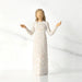 Willow Tree® Front view of brunette girl figurine in white dress with gold dots holding her hands to the side
